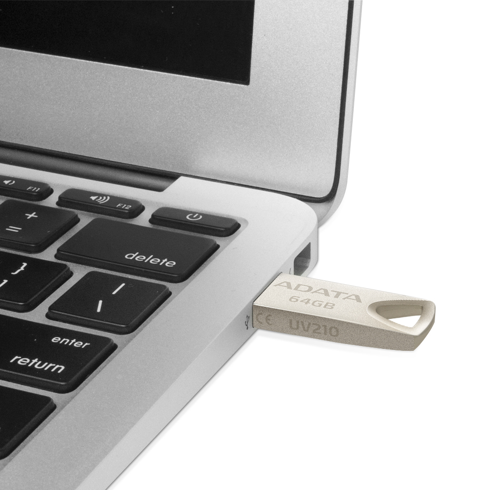 Srebrny i czarny pendrive włożony do srebrnego laptopa. Dysk jest oznaczony jako ADATA 64GB.