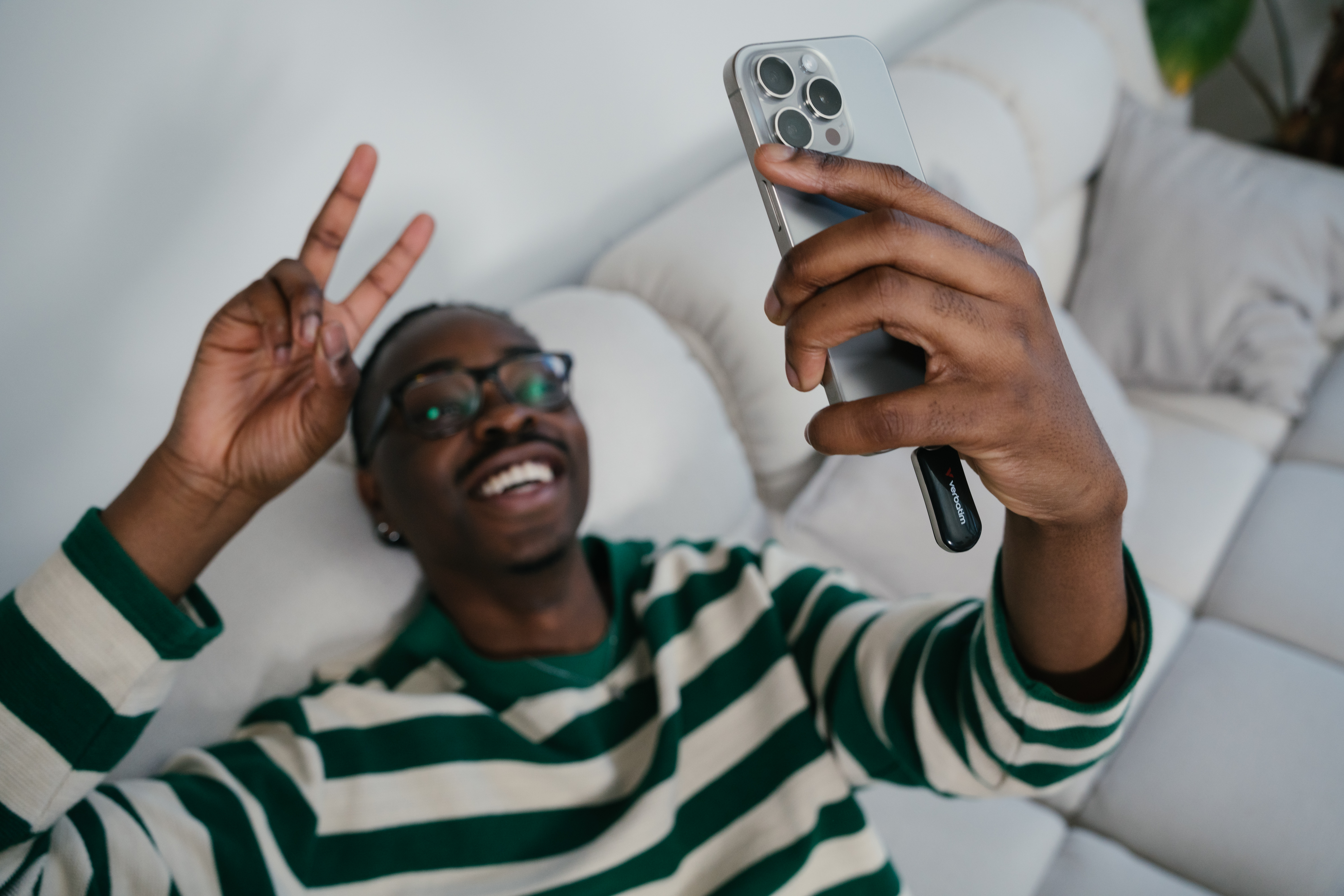 Mężczyzna robi selfie telefonem. Uśmiecha się i pokazuje znak pokoju.