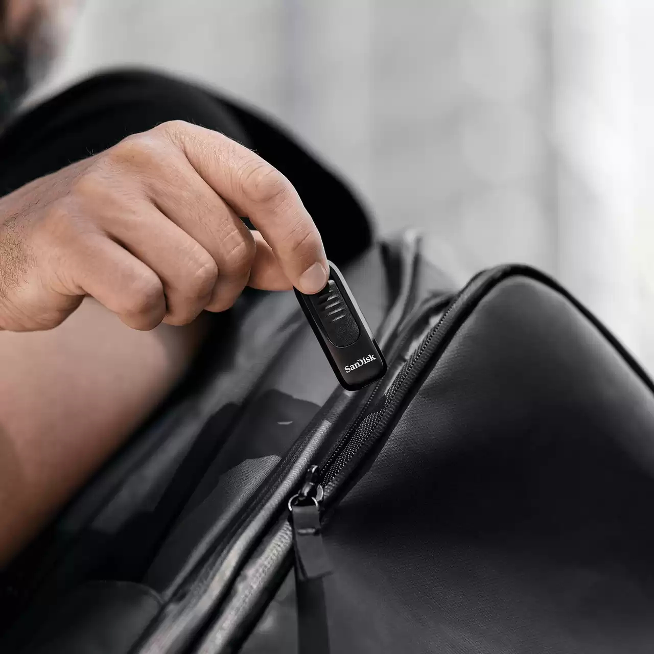 Ręka wyjmuje czarnego pendrive'a z czarnej torby. Torba jest zamykana na zamek.