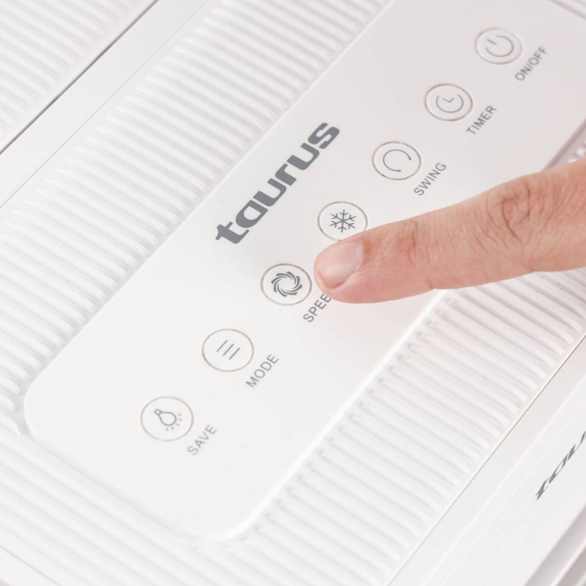 Una mano presiona el botón 'velocidad' en un panel de control Taurus blanco.
