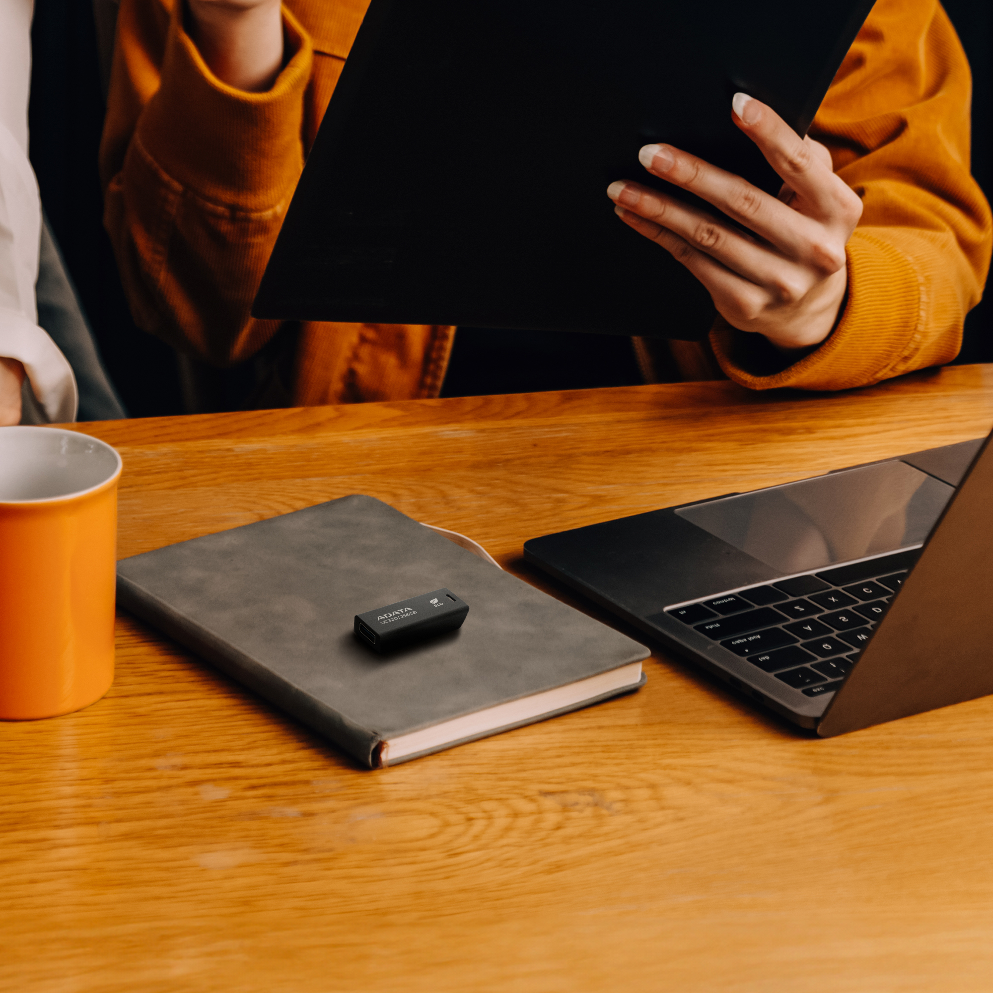 Pendrive na notatniku w pobliżu laptopa i kubka.