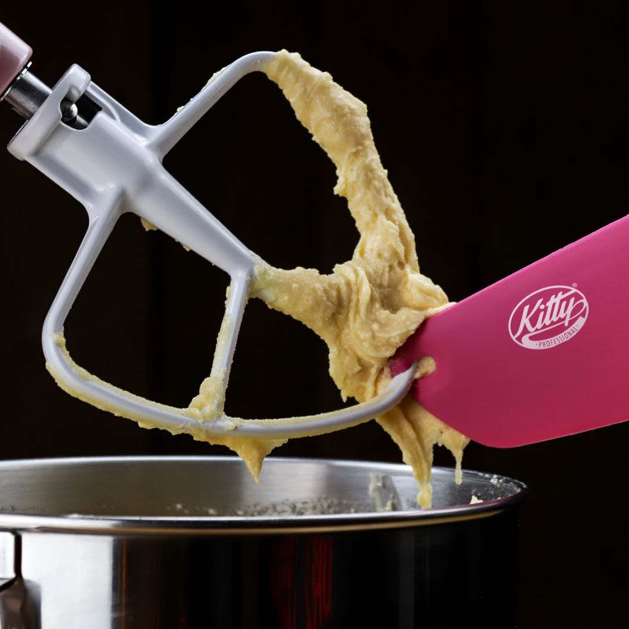 Ein Mixer und ein rosa Spatel verrühren Teig in einer Metallschüssel. Auf dem Spatel steht das Wort Kitty.