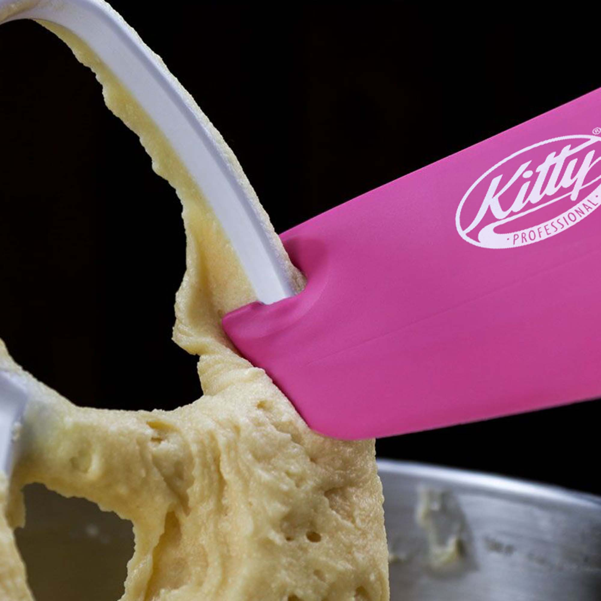 Nahaufnahme eines rosa Spatels, der Teig von einem Mixer-Schläger abkratzt. Kitty Professional Logo sichtbar.