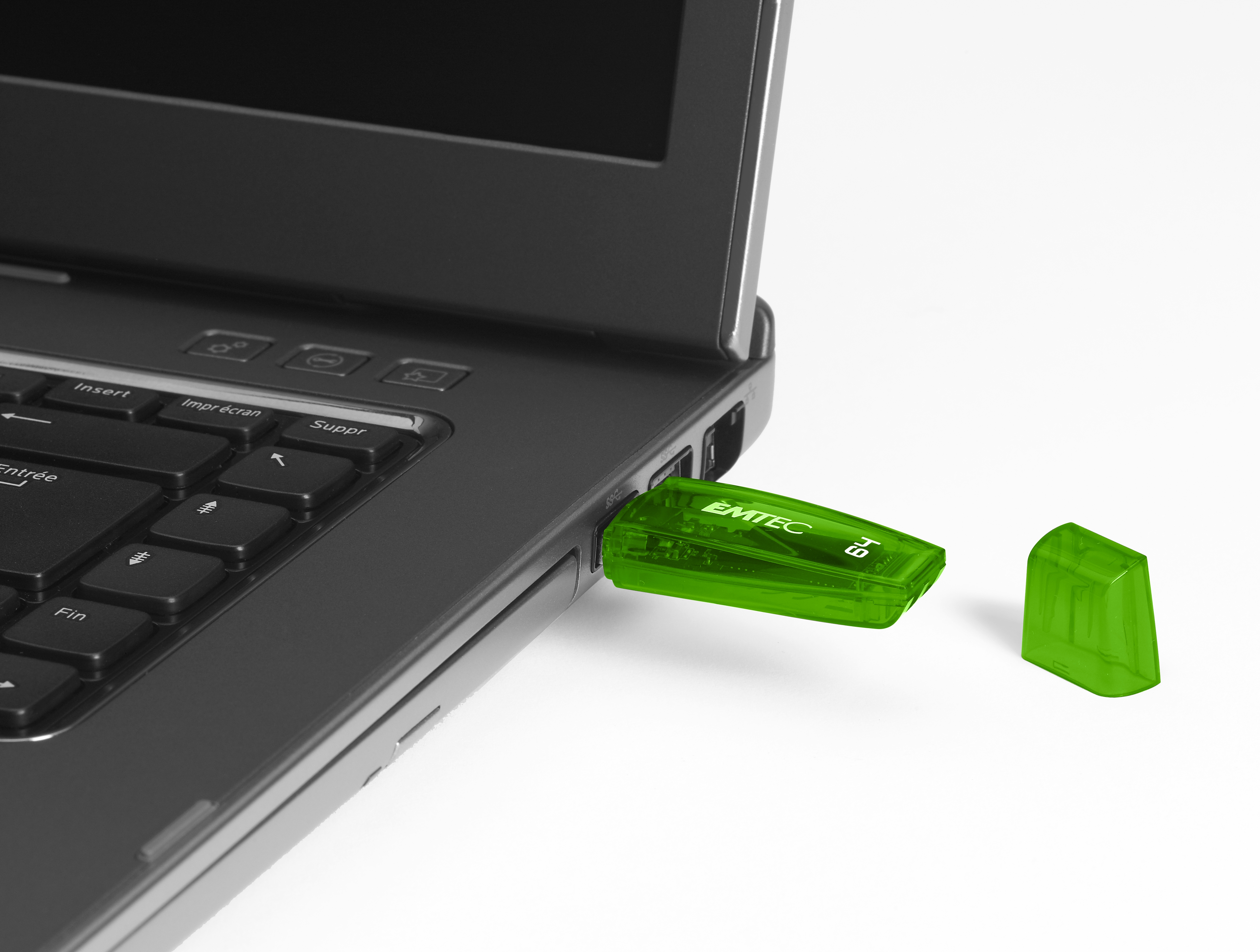 Zielony pendrive podłączony do laptopa. Białe tło.