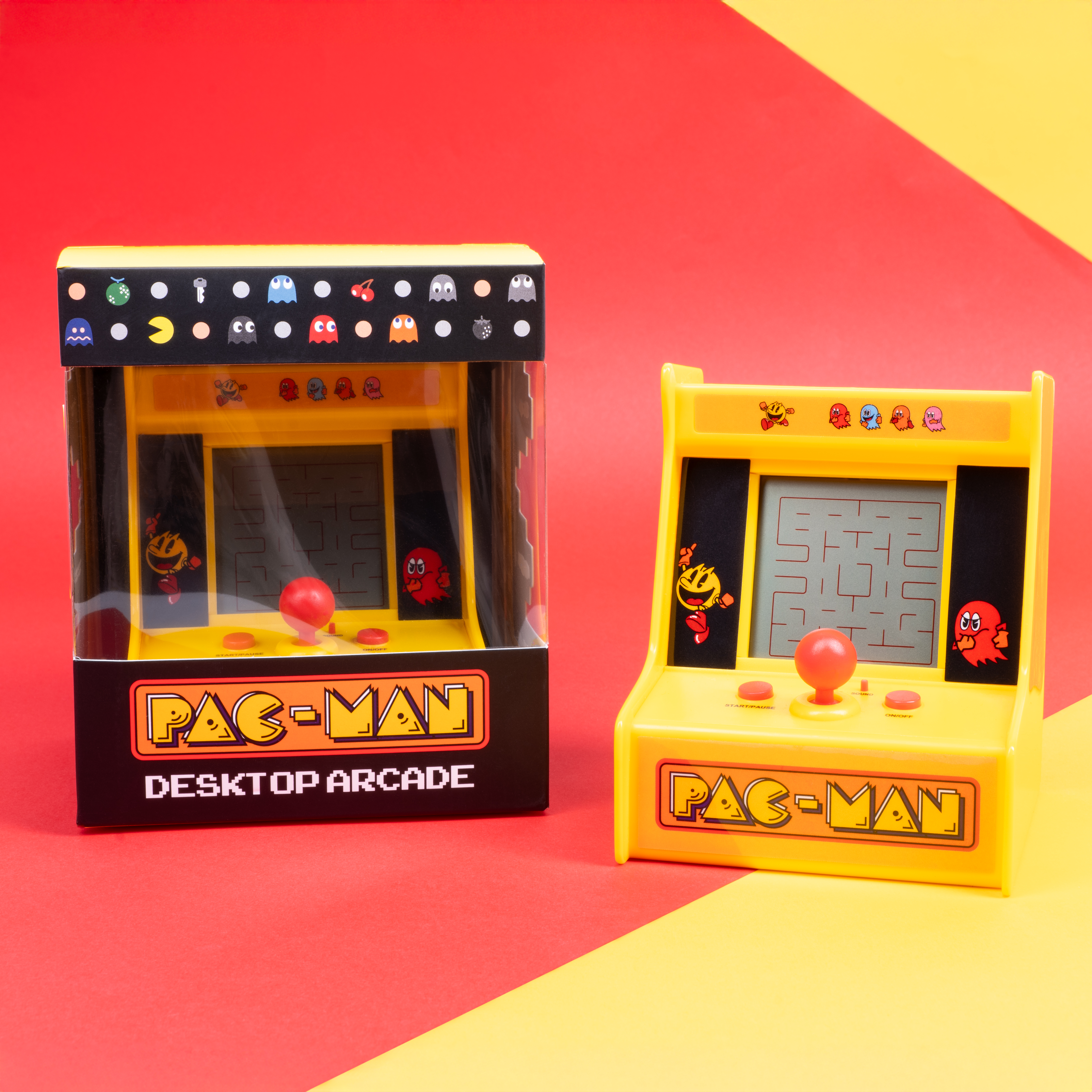 Twee gele Pac-Man arcadekasten op een rode en gele ondergrond. Eén in een doos.