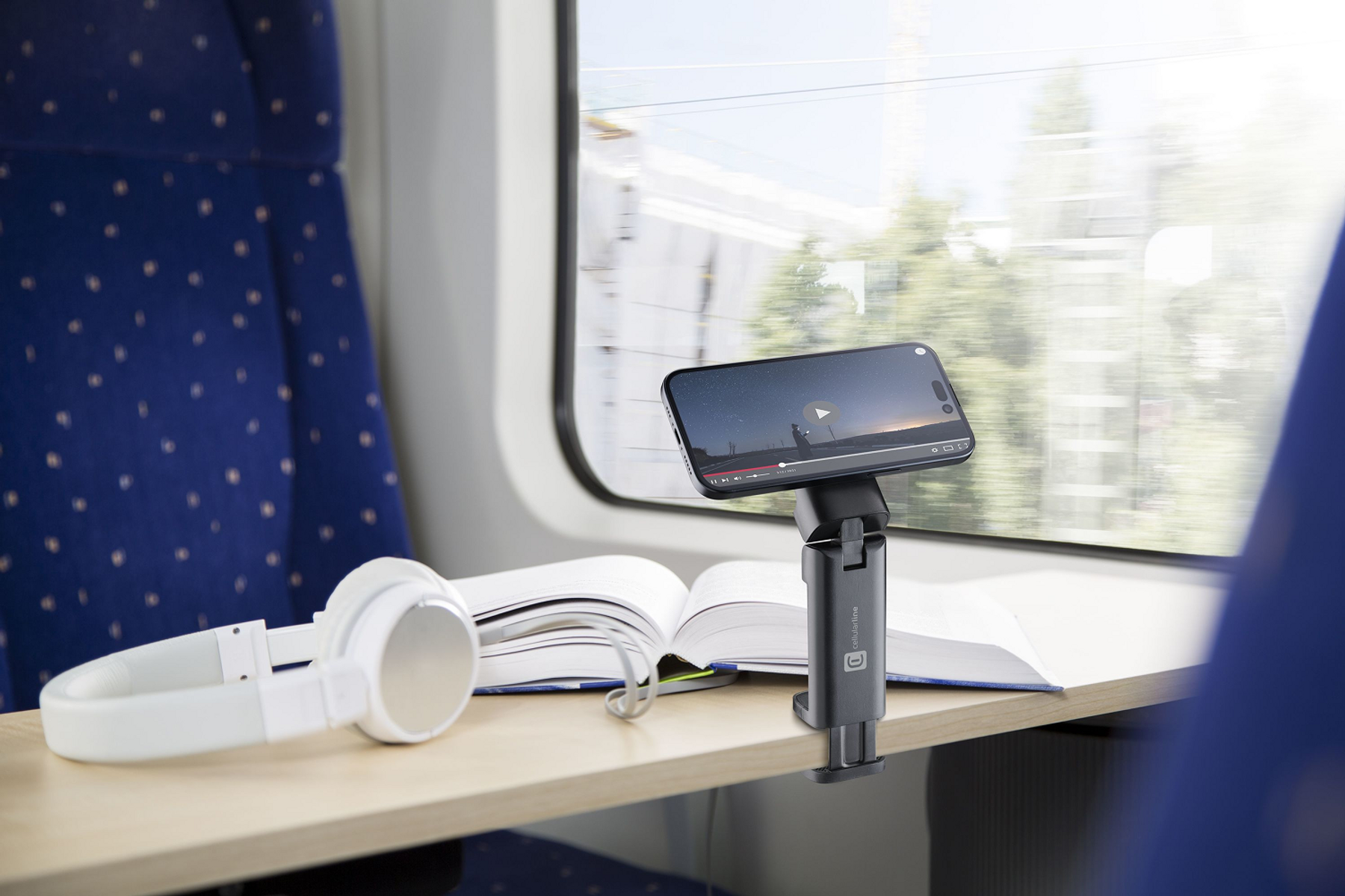 Smartphone en un soporte, en una mesa en un tren, con auriculares.