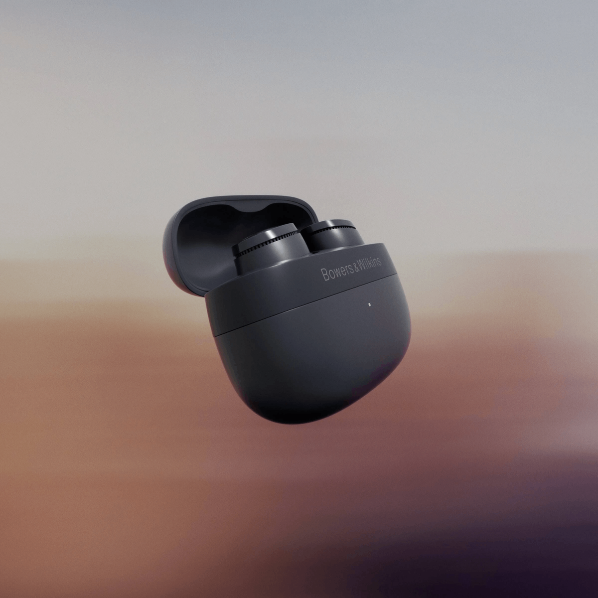 Czarne słuchawki Bowers & Wilkins w otwartym etui na rozmytym pomarańczowo-szarym tle.