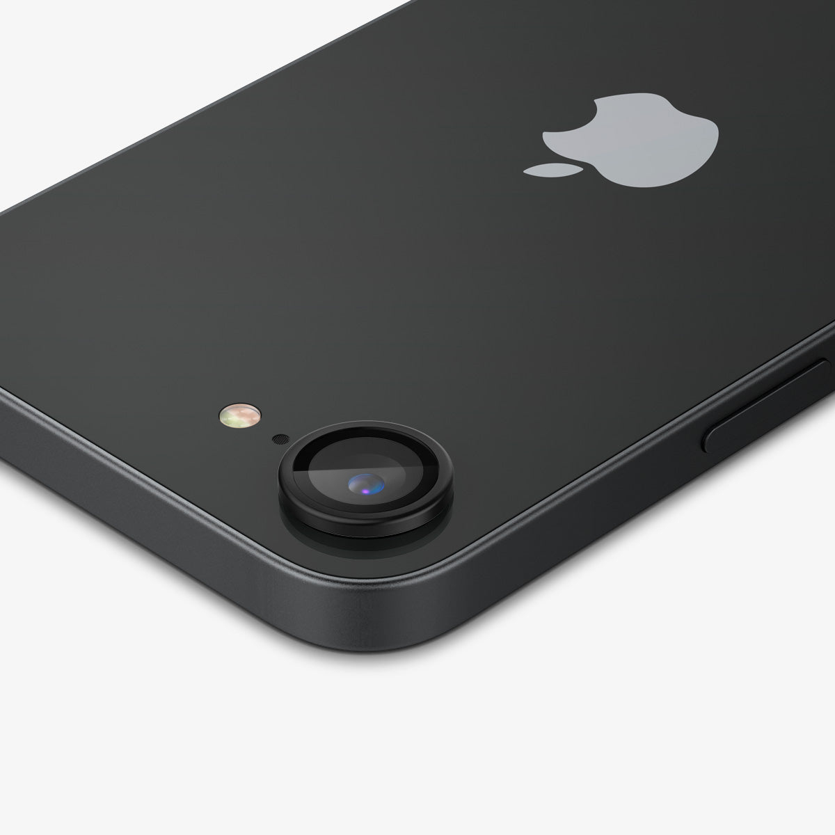 Ciemny telefon z nałożoną jedną osłoną obiektywu aparatu. Widoczne logo Apple.