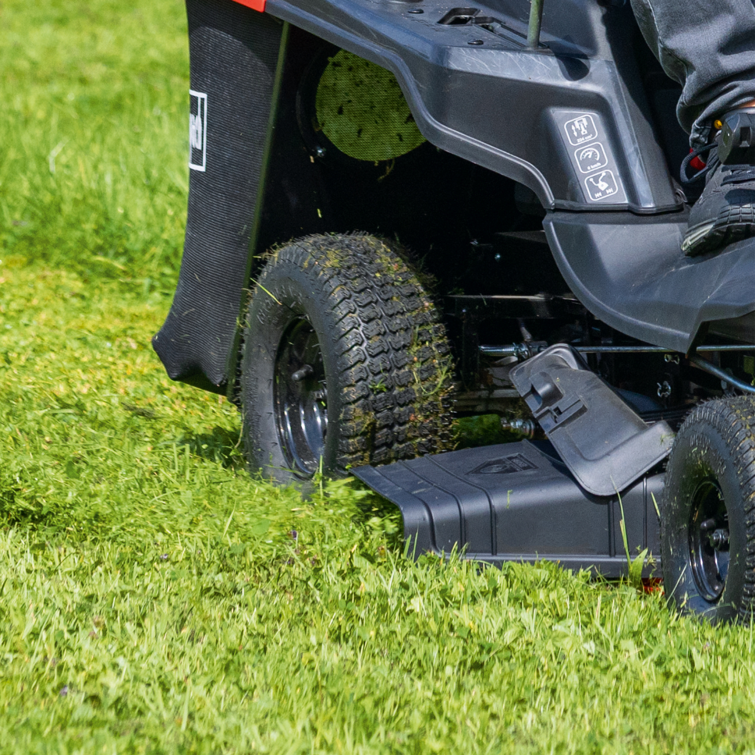 Een zitmaaier die gras maait. Een persoon zit op de maaier.