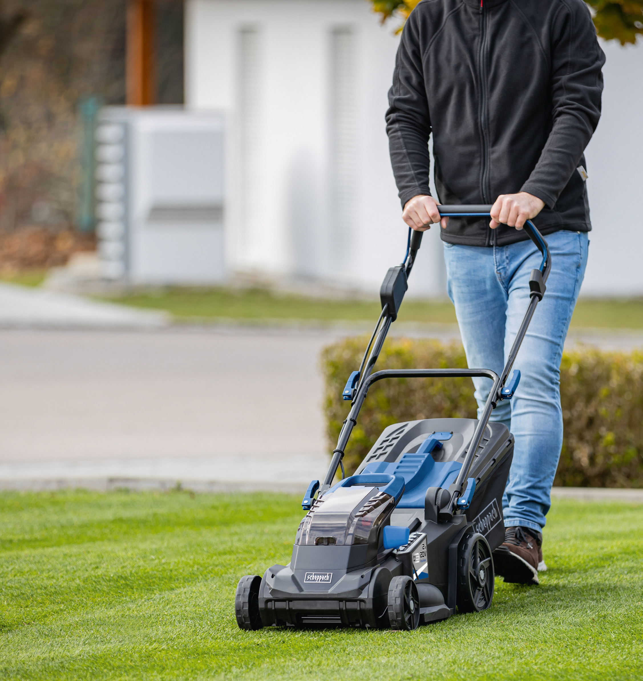 Persoon die een grasmaaier gebruikt op groen gras. De grasmaaier is zwart en blauw.