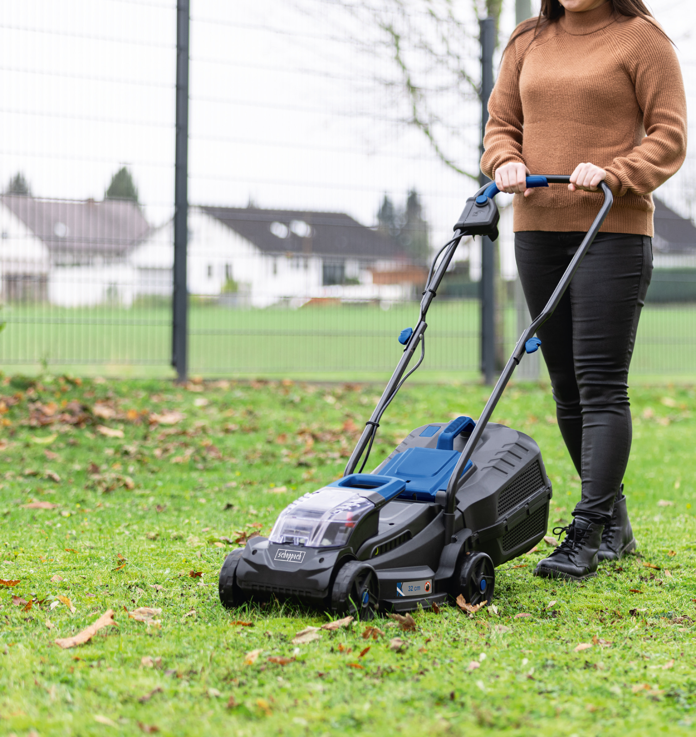 Een vrouw duwt een blauw-zwarte grasmaaier op een groen gazon.