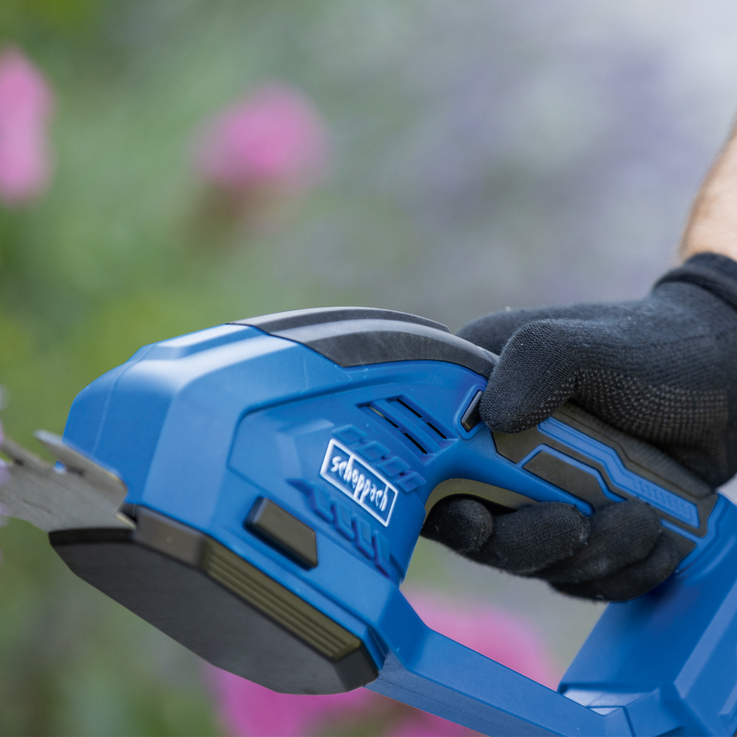 De hand van een persoon die een blauwe heggenschaar gebruikt.