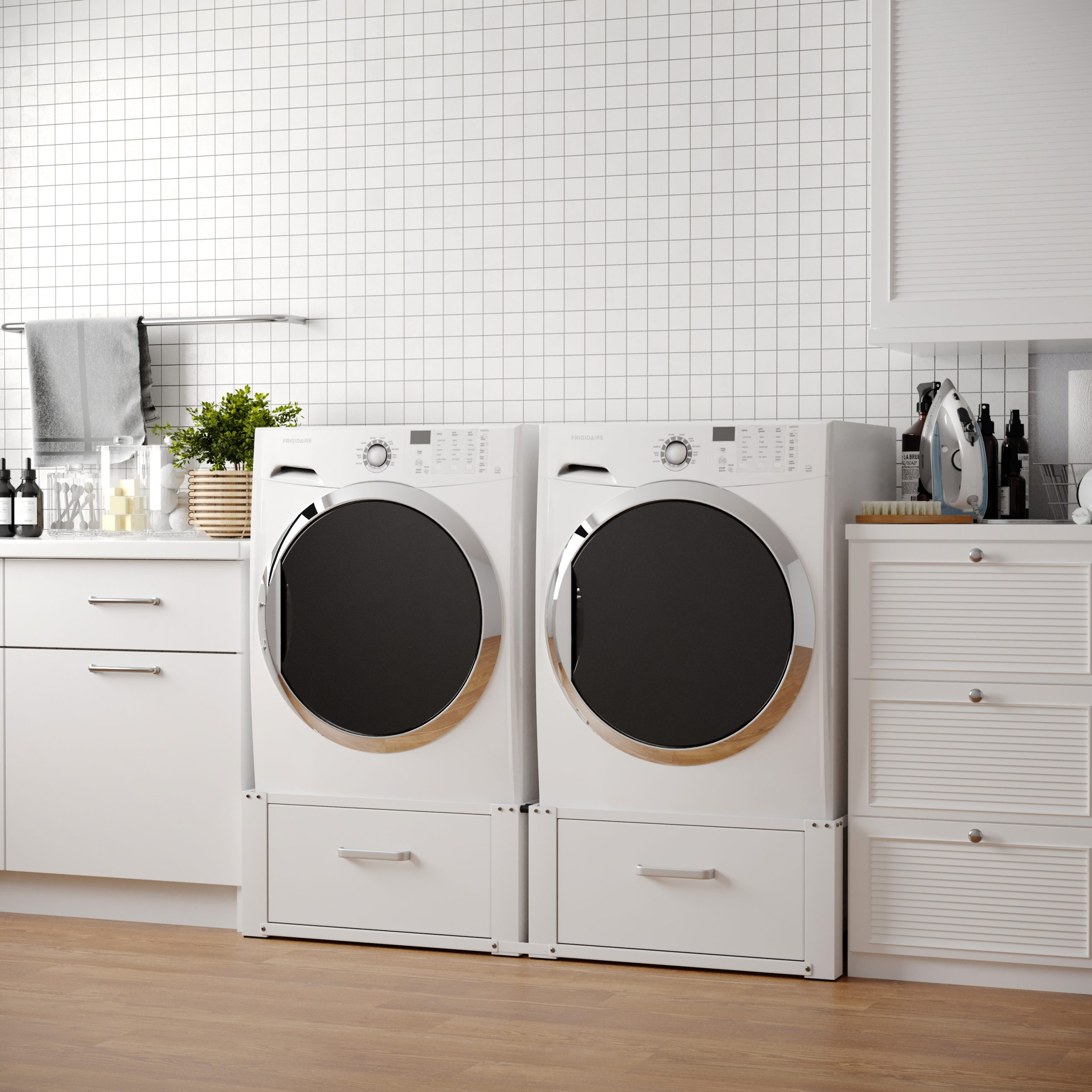 Zwei weiße Waschmaschinen mit Frontlader auf Sockeln in einem Waschraum mit weißer Fliesenwand.