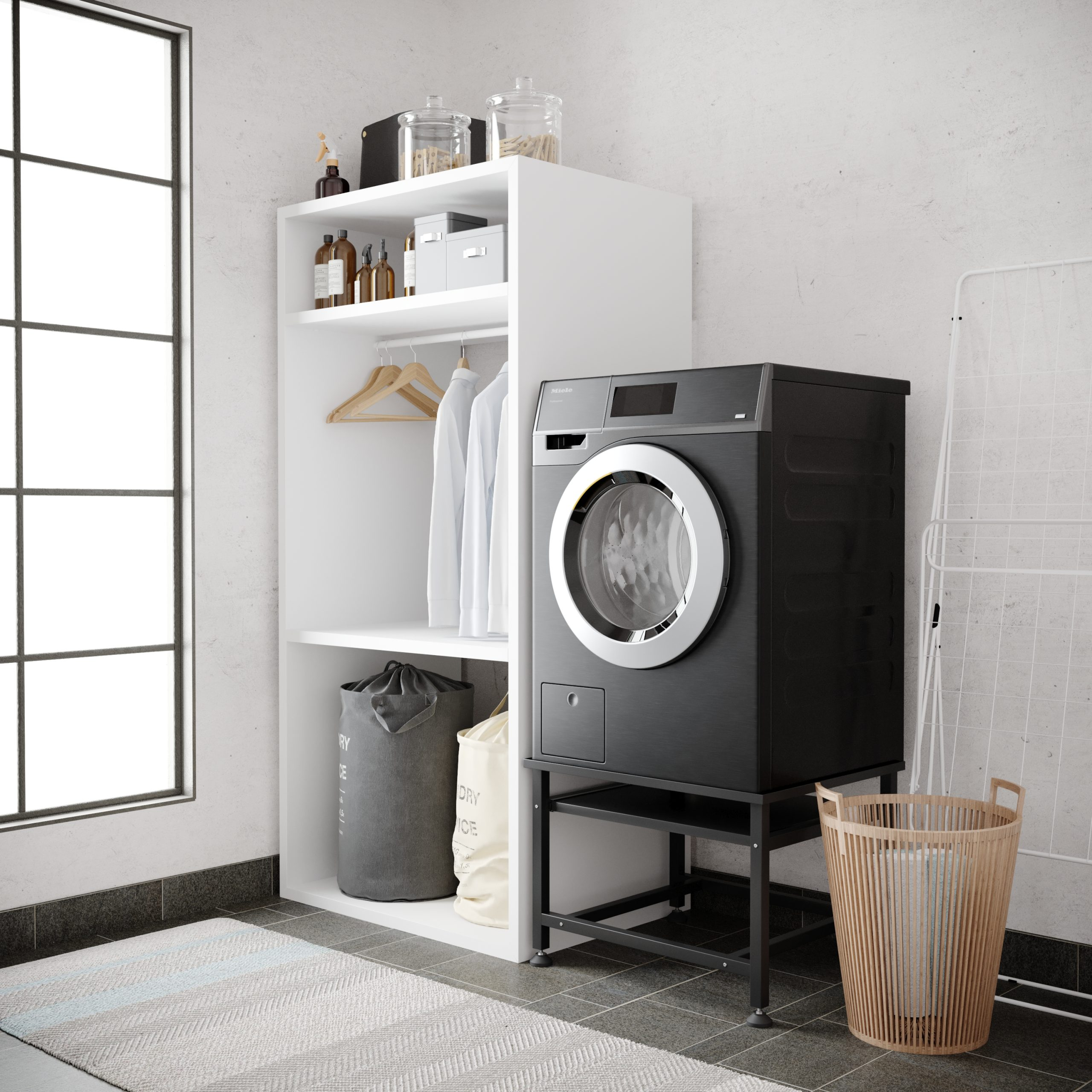 Waschküche mit einer schwarzen Waschmaschine und einem weißen Schrank, hängender Kleidung und einem Wäschekorb.