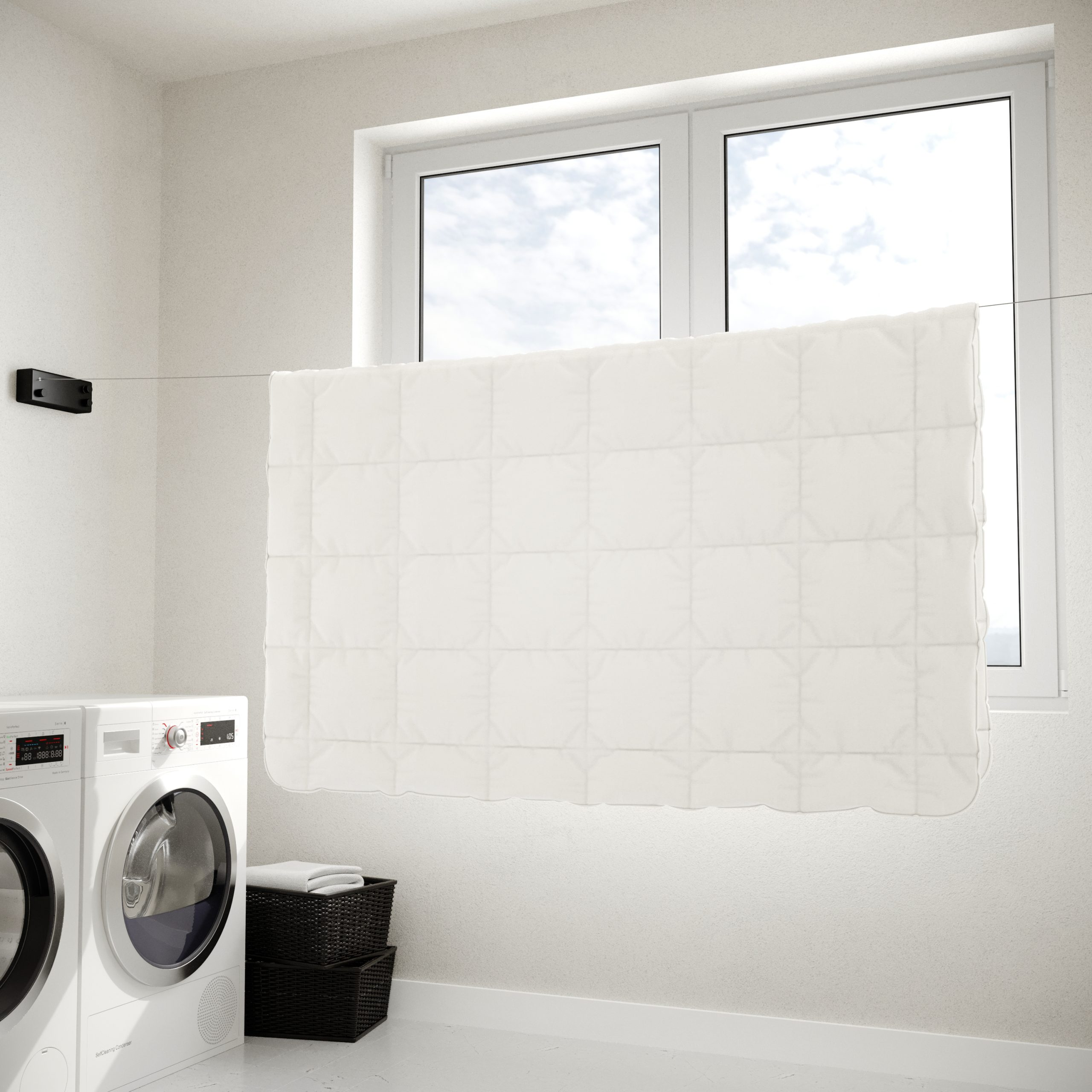 Buanderie avec une couette blanche suspendue devant une fenêtre. Machine à laver en vue.