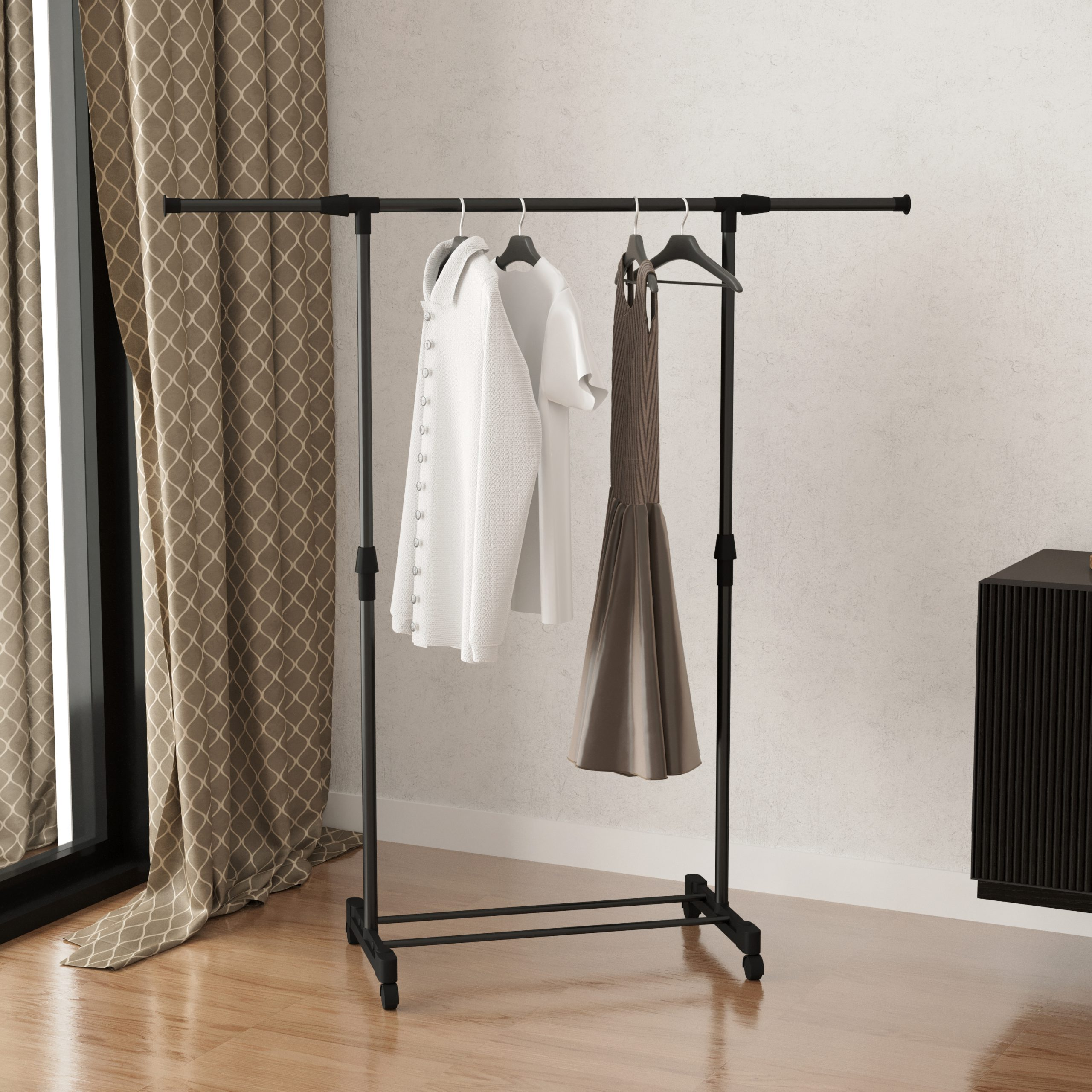 Black clothes rack with clothes hanging. The room has a window and a wooden floor.