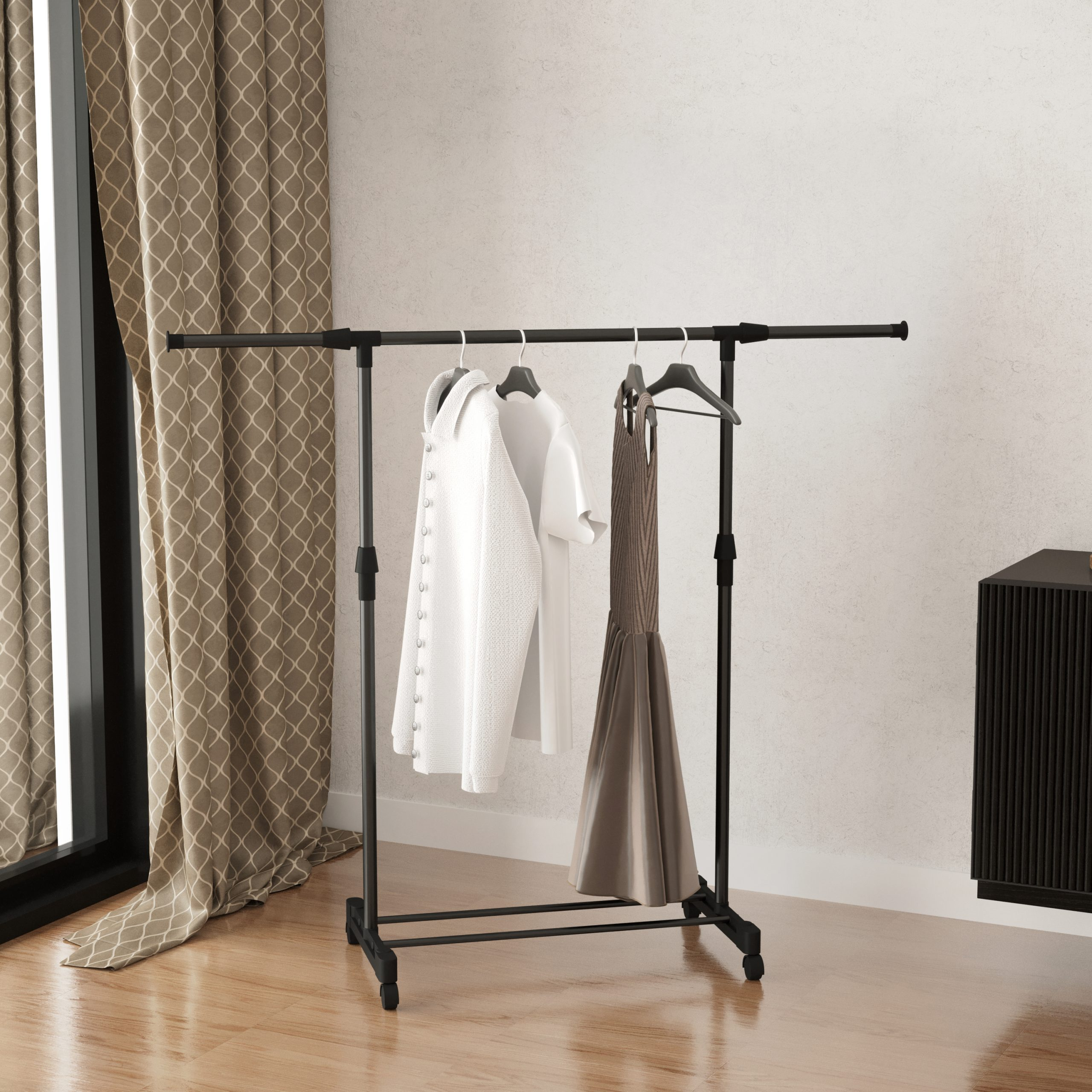 A black clothes rack with clothes on hangers, on a wooden floor.