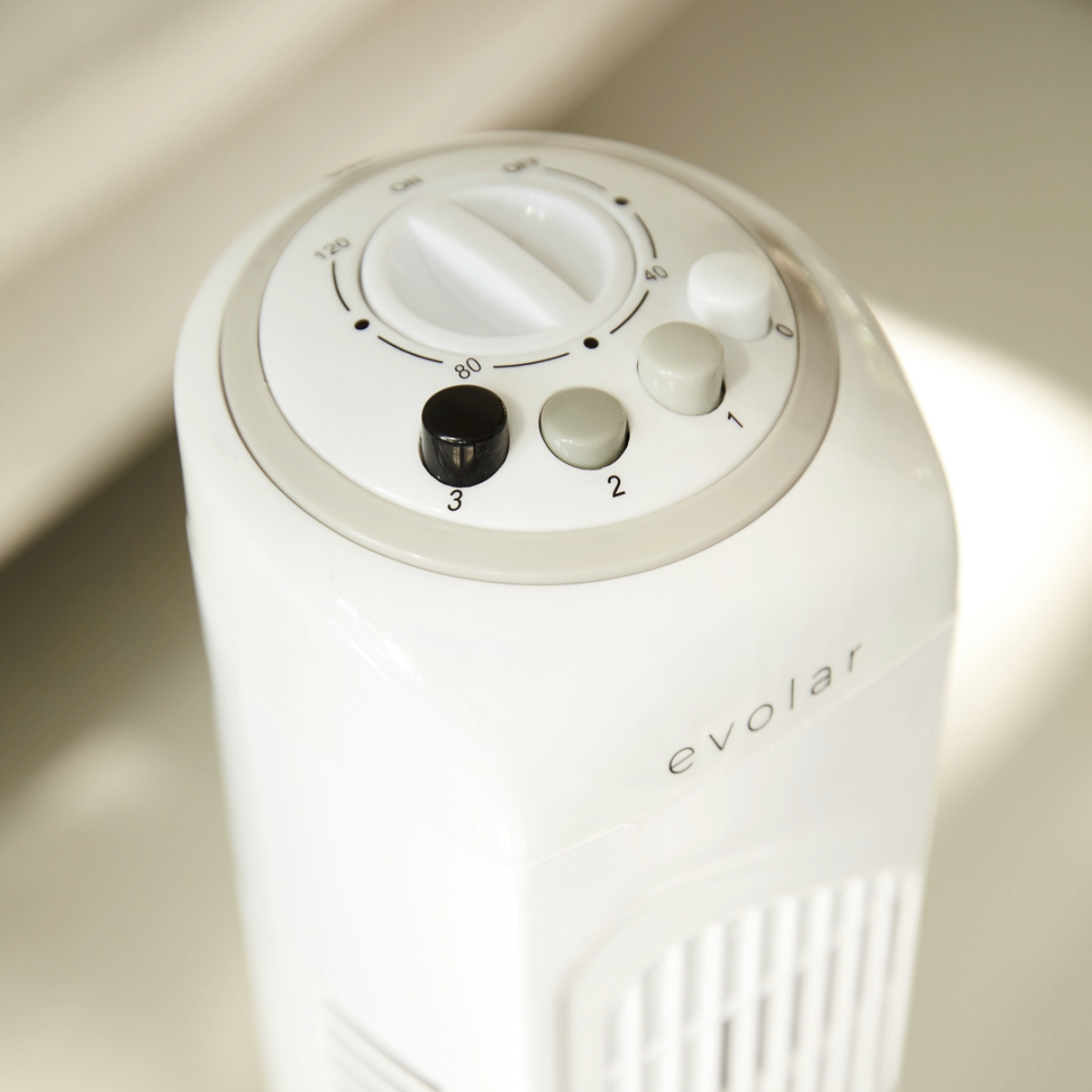 A close-up of a white fan control panel with buttons and a dial. The word 'Evolar' is below.