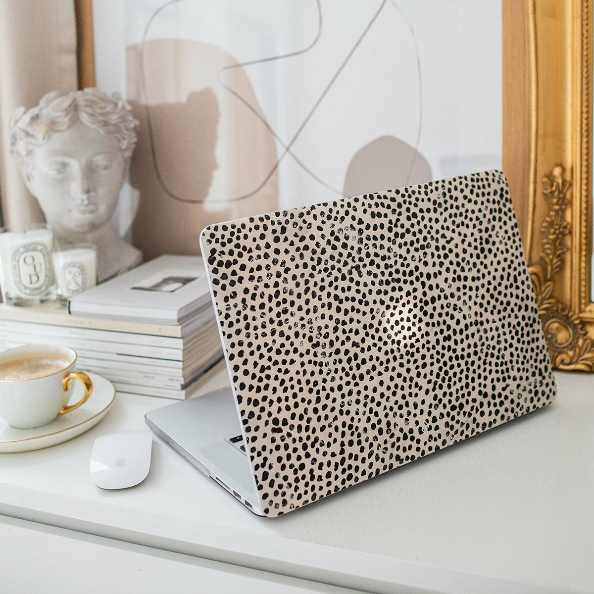 Laptop su una scrivania con una cover. Oggetti decorativi sullo sfondo.