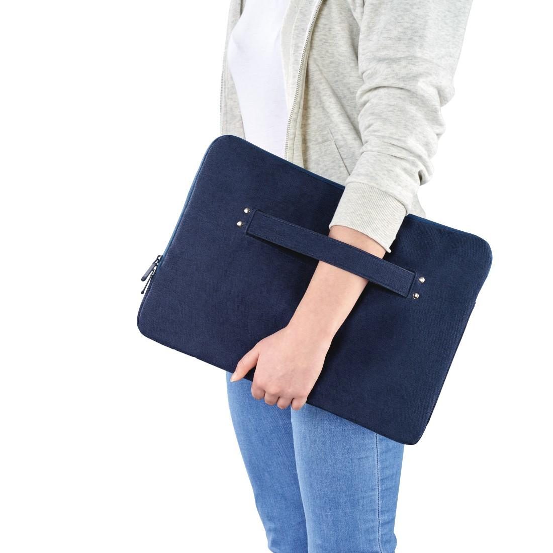 Osoba trzyma granatową torbę na laptopa. Widoczne dżinsy i szara bluza z kapturem.