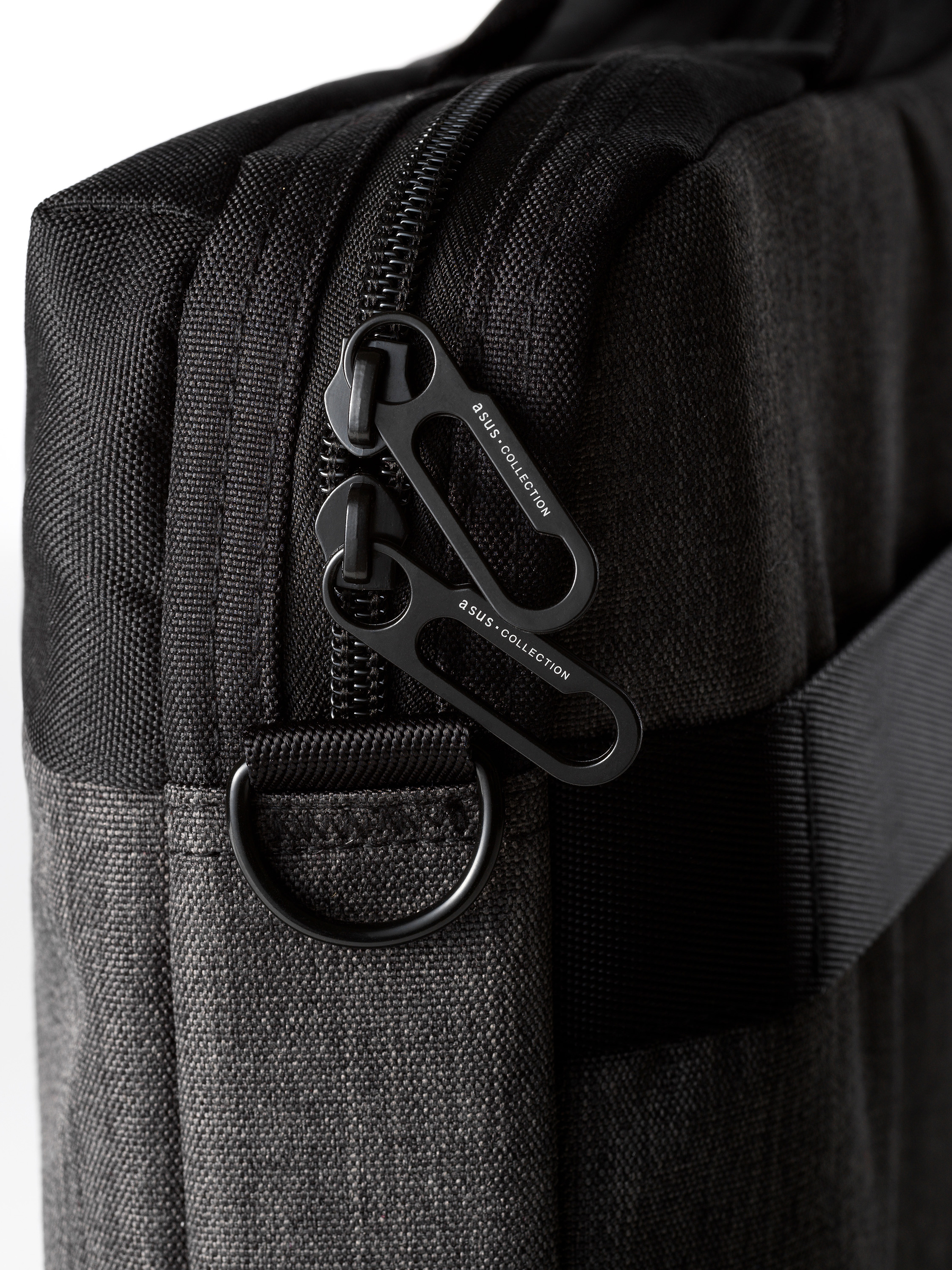 Primo piano di una borsa nera con due tiretti, etichettata con ASUS COLLECTION. Sfondo bianco.