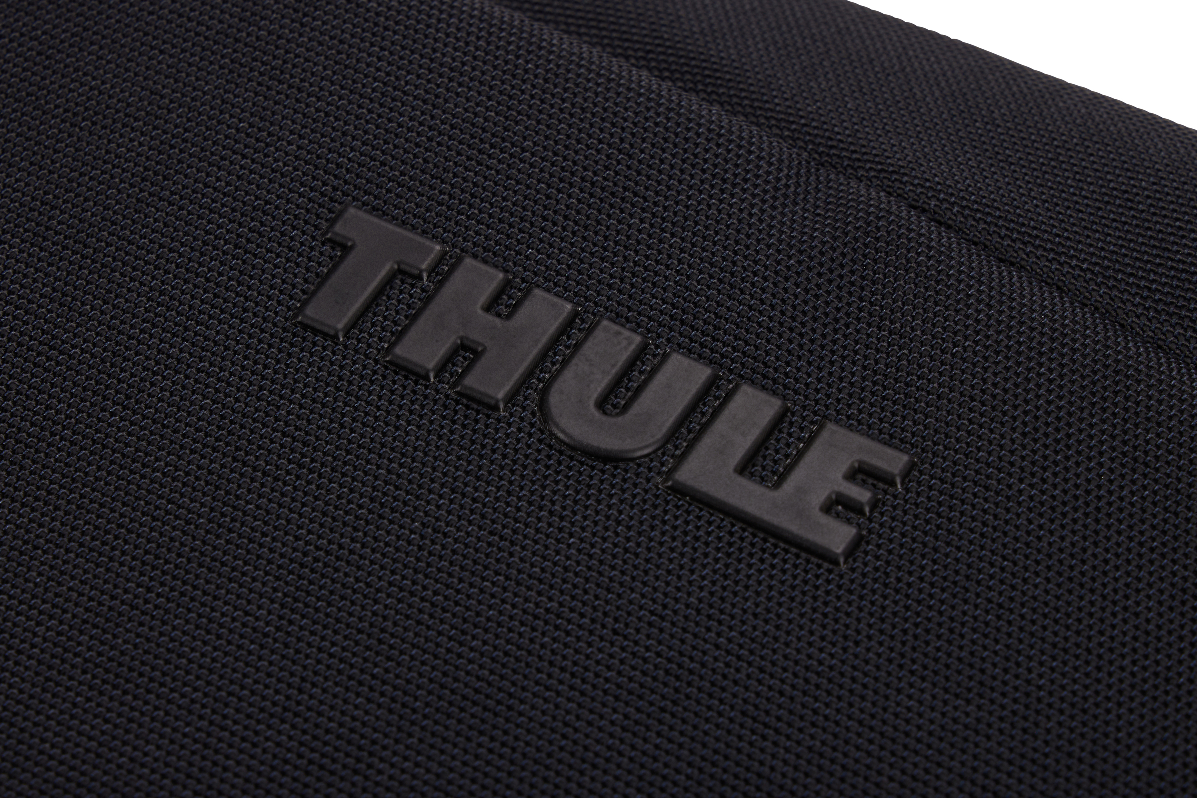 Primo piano del logo 'THULE' nero, impresso su tessuto nero strutturato.