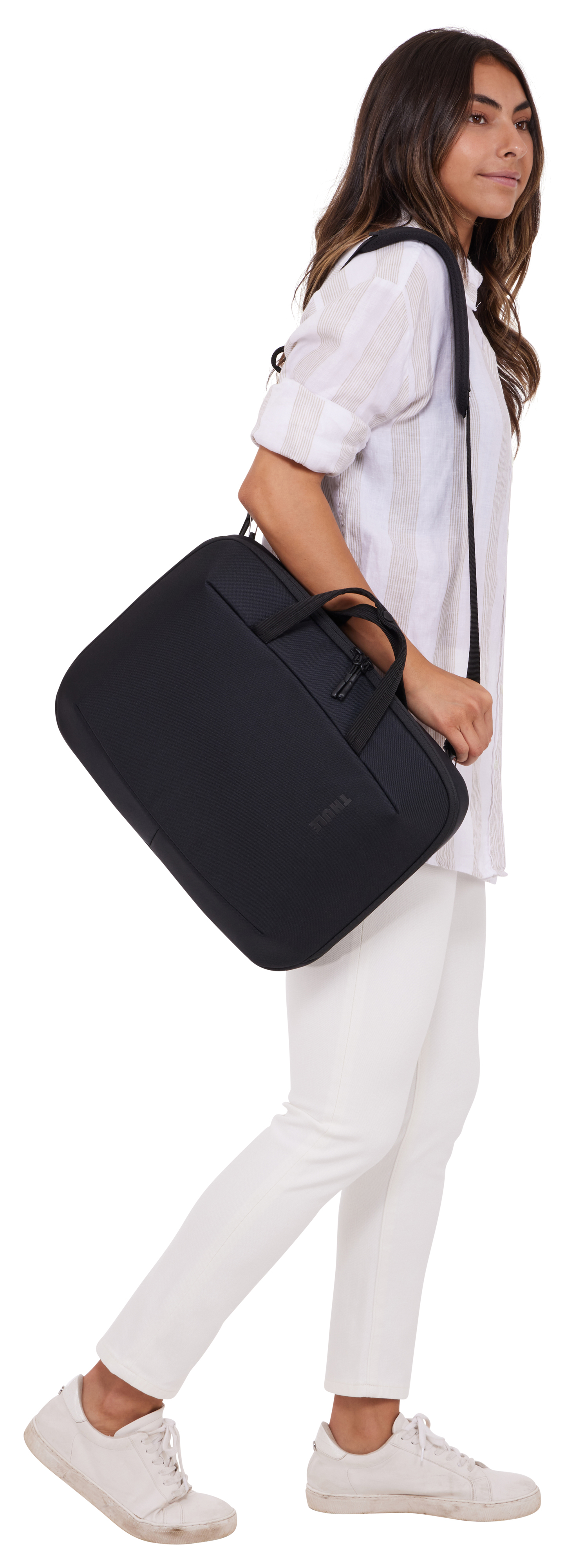 Donna che cammina, porta una borsa nera per laptop sulla spalla. Pantaloni bianchi.
