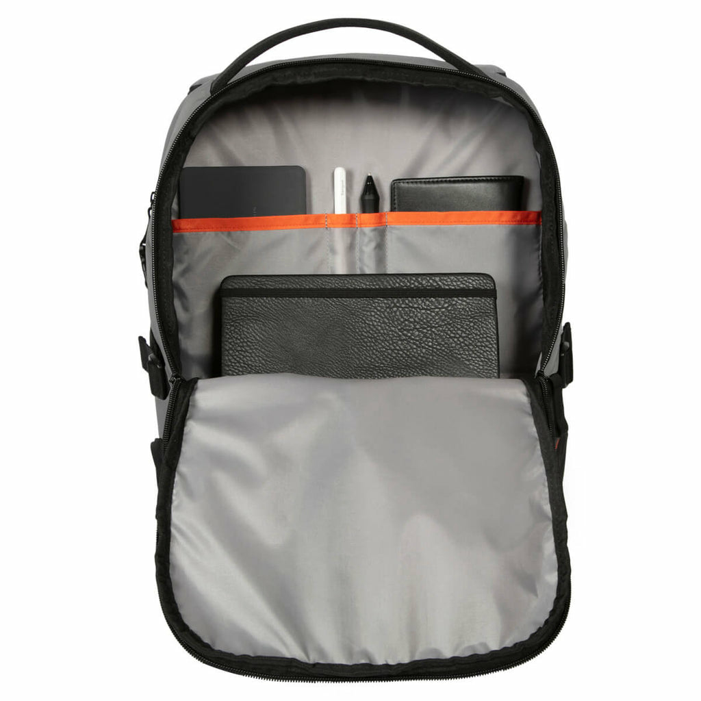 Zaino grigio aperto con tasche interne. Gli articoli includono un blocco note nero, penne e accessori.