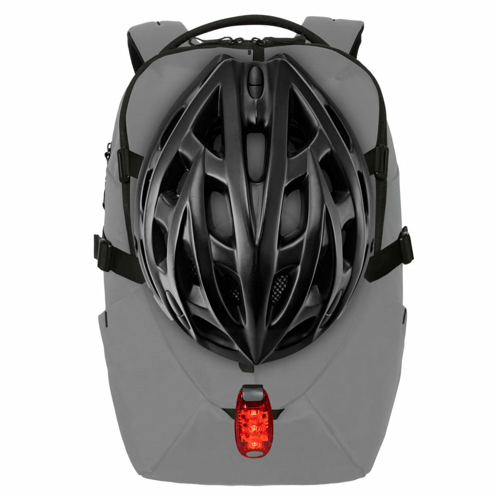Uno zaino grigio con un casco nero sulla schiena. C'è una luce rossa in basso.