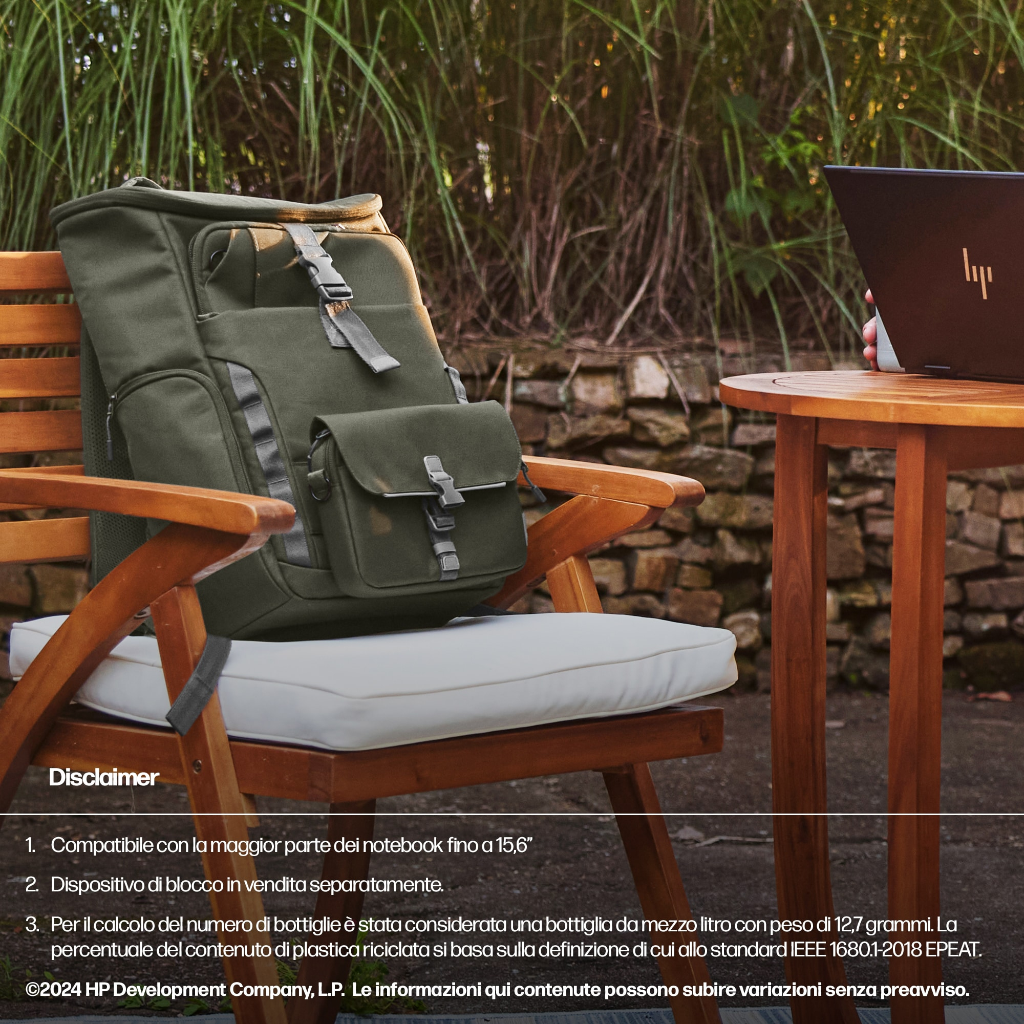 Zaino per laptop su una sedia di legno all'aperto, vicino alle piante, con un laptop su un tavolo.