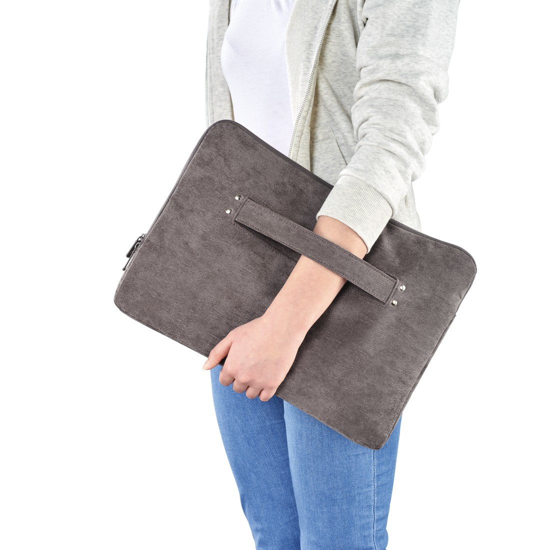 Eine Person hält eine graue Laptoptasche. Die Tasche hat einen Griff. Die Person trägt einen Kapuzenpullover und Jeans.