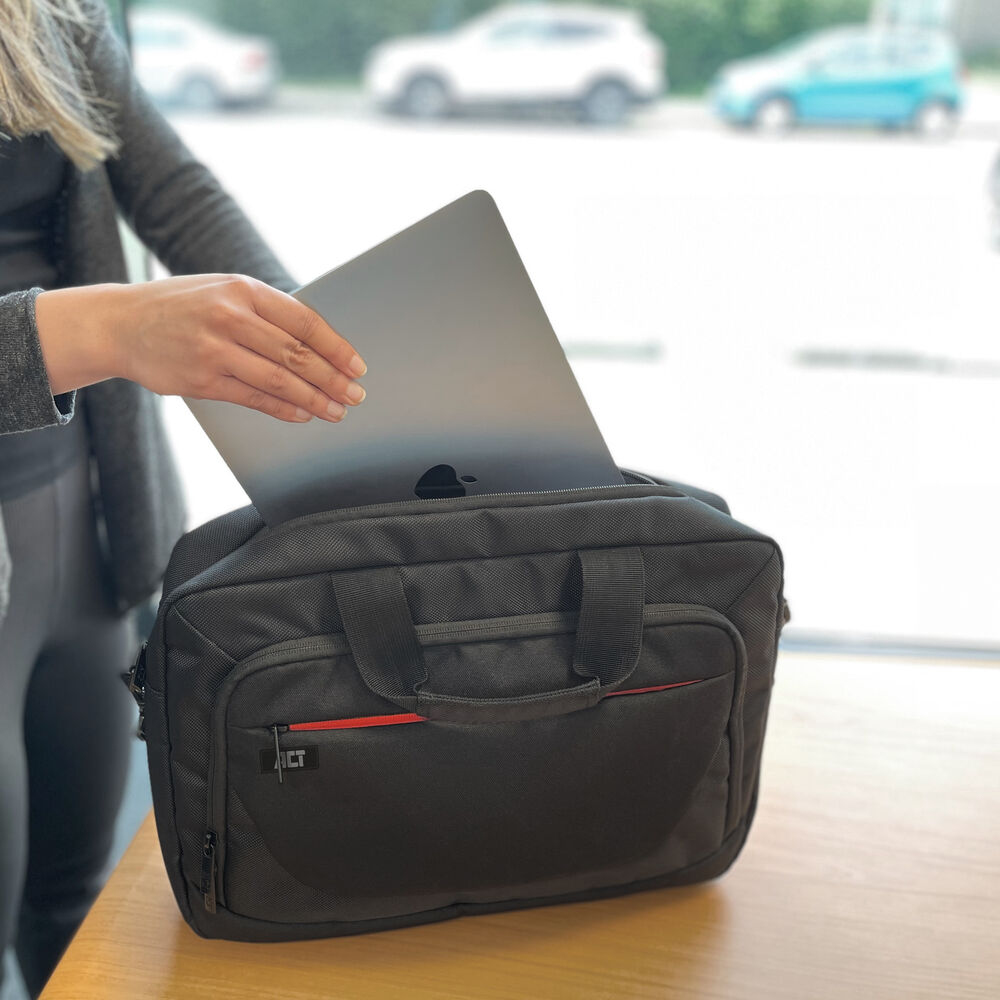 Una donna mette un laptop in una borsa nera. Sfondo: finestre, auto.