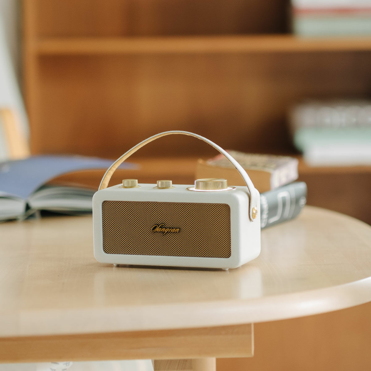 Radio blanco y dorado de estilo retro sobre una mesa con libros.