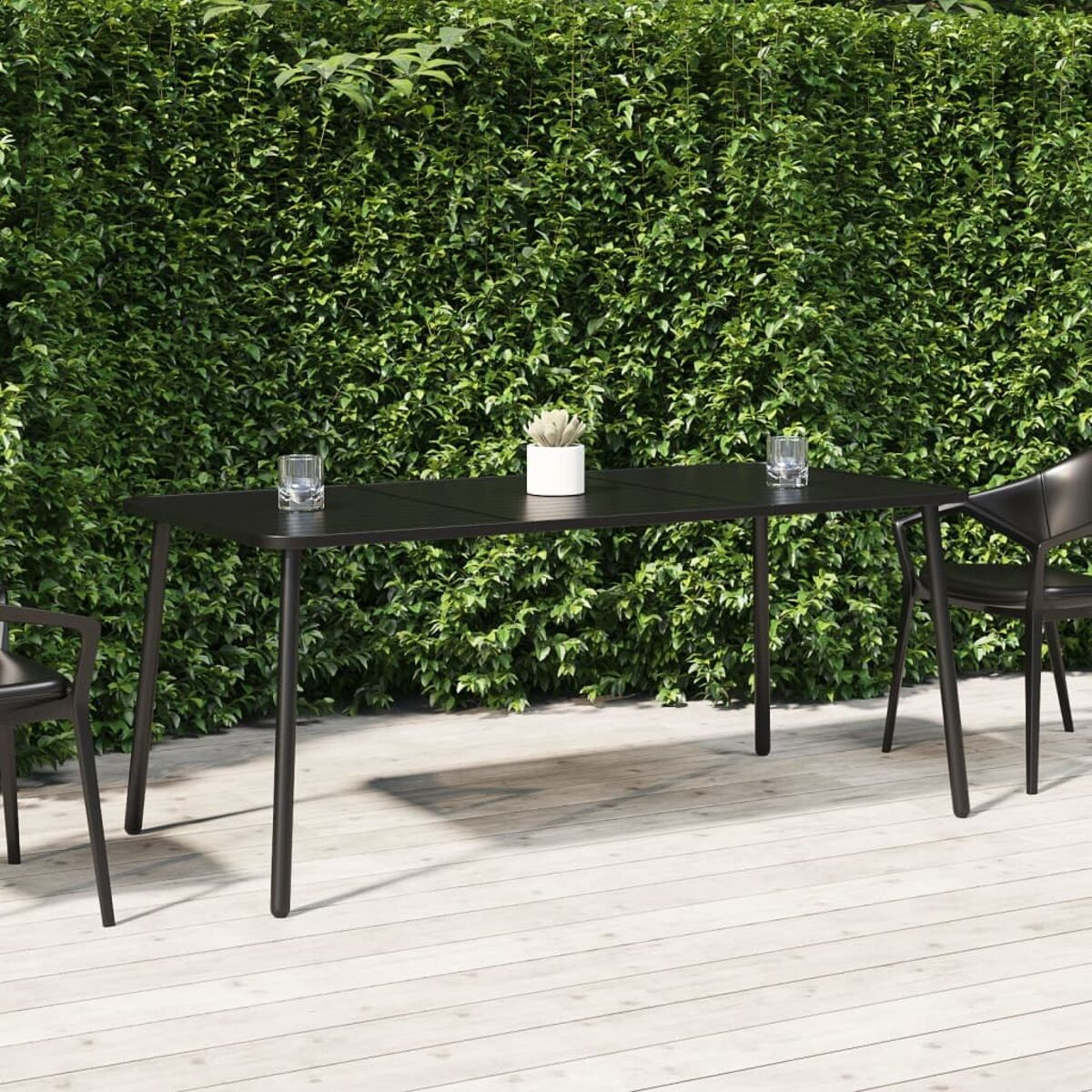 Schwarzes Ess-Set im Freien auf Holzterrasse. Schwarzer Tisch mit vier Stühlen und Hecke.