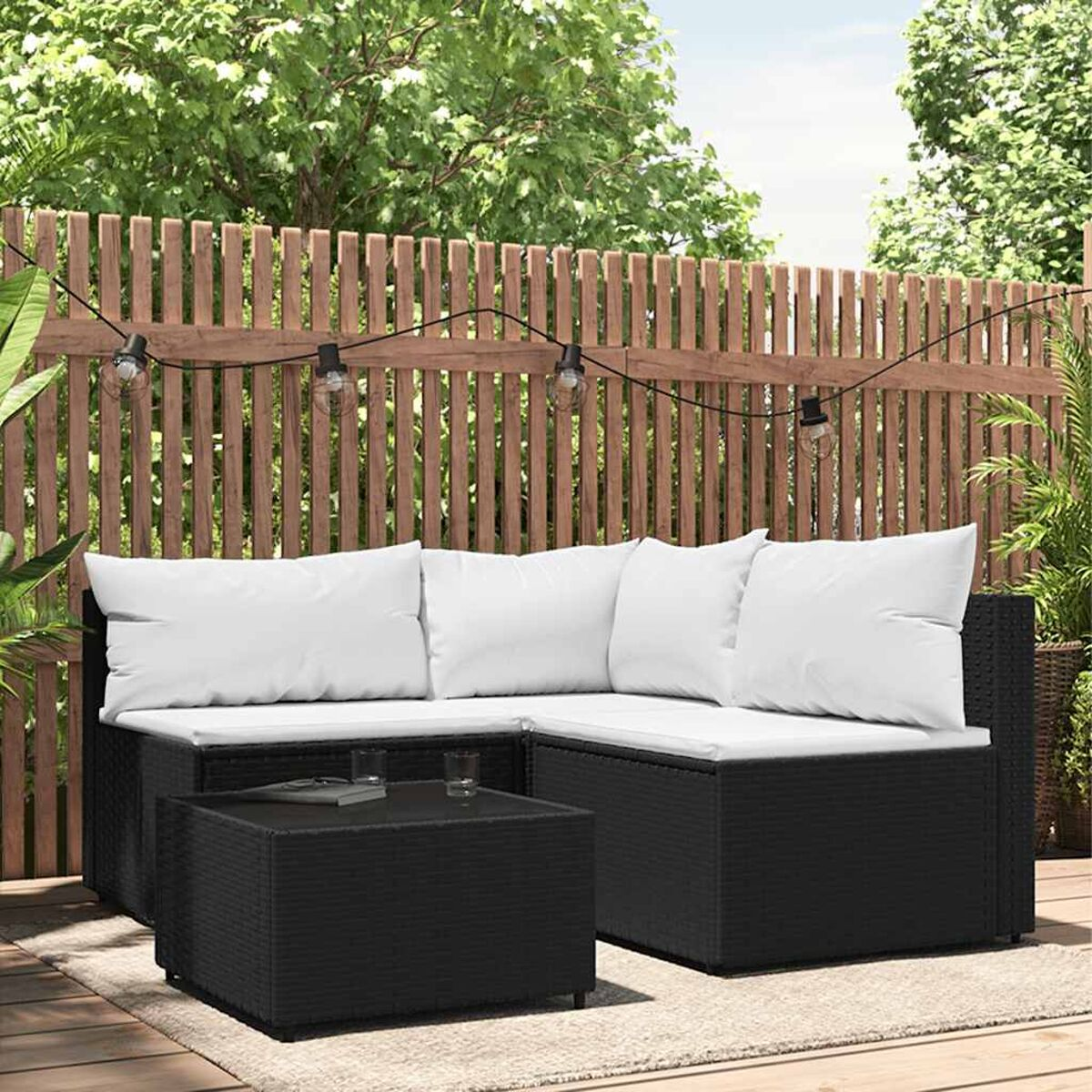 Schwarzes Rattan-Ecksofa mit weißen Kissen und passendem Couchtisch im Garten.