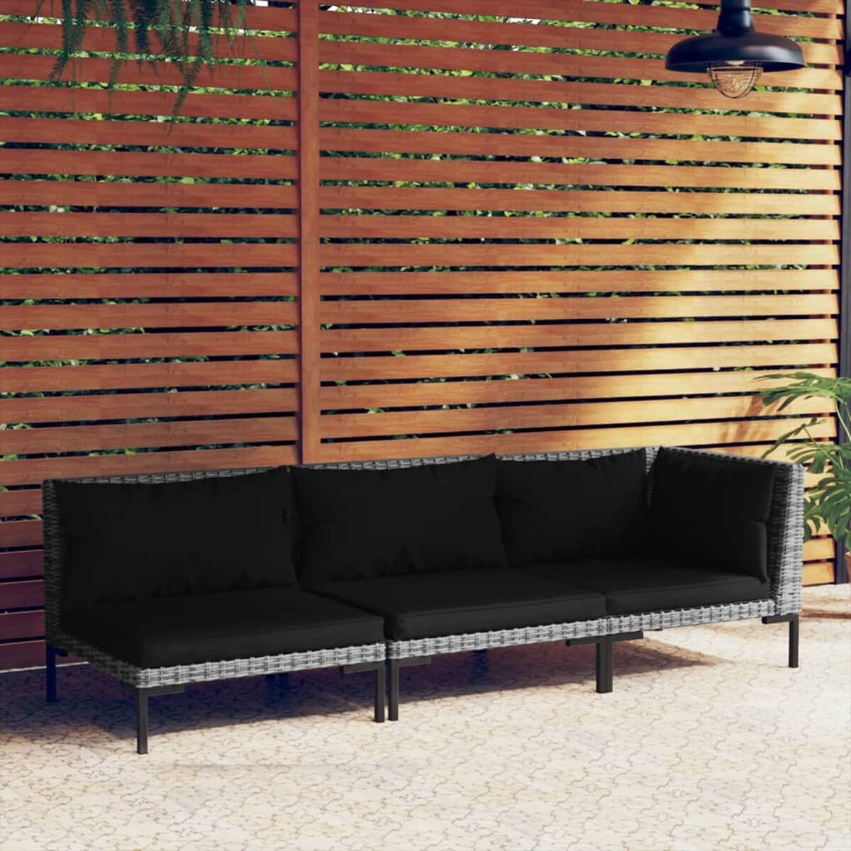 Outdoor-Sofagarnitur. Schwarze Kissen, grauer Rahmen. Brauner Holzzaun und Wand im Hintergrund.
