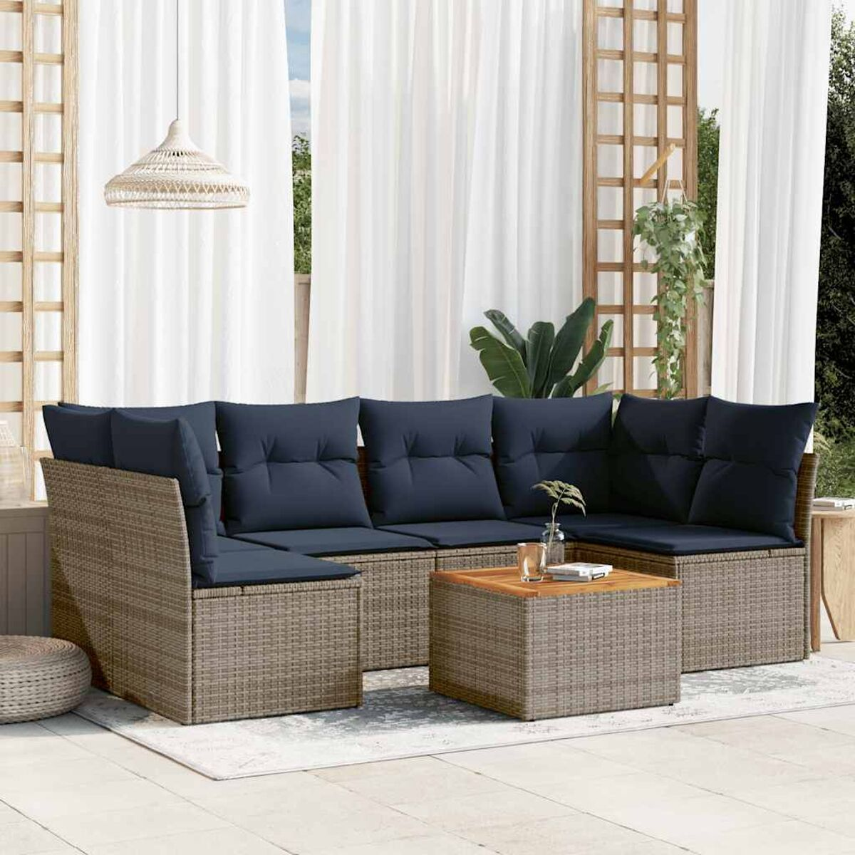 Set patio in vimini con cuscini blu, un tavolino e un tappeto, contesto esterno.