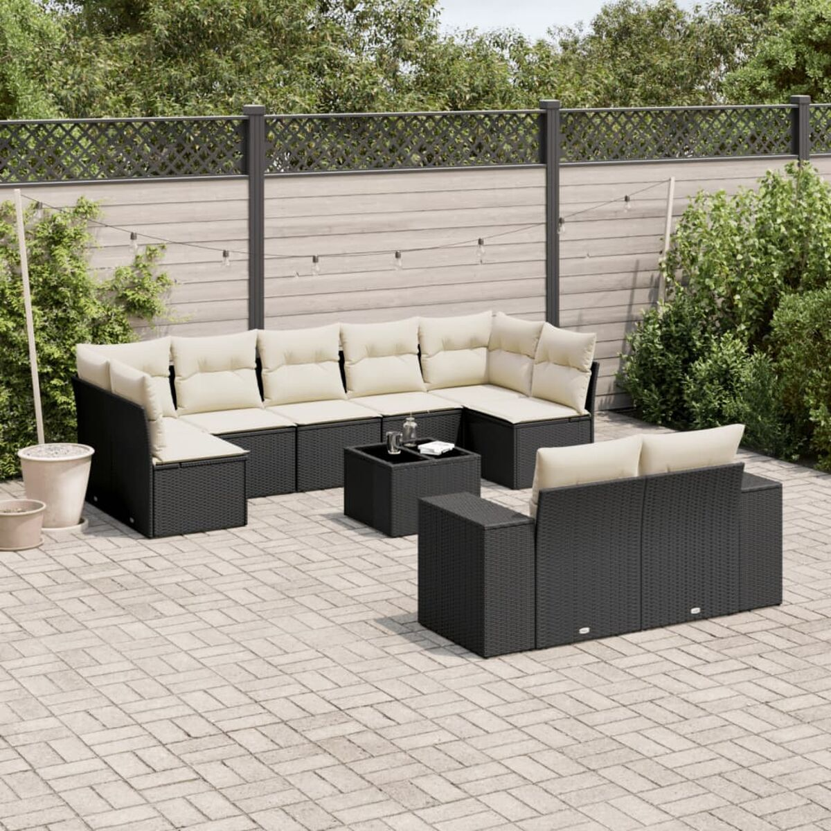 Schwarzes Outdoor-Geflechtmöbel-Set auf einer Terrasse. Das Set umfasst ein Ecksofa, einen Couchtisch und einen Einzelstuhl.