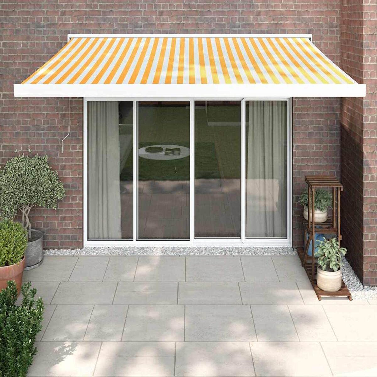 Hausfassade mit gestreifter Markise, Glastüren und Topfpflanzen auf einer Terrasse.