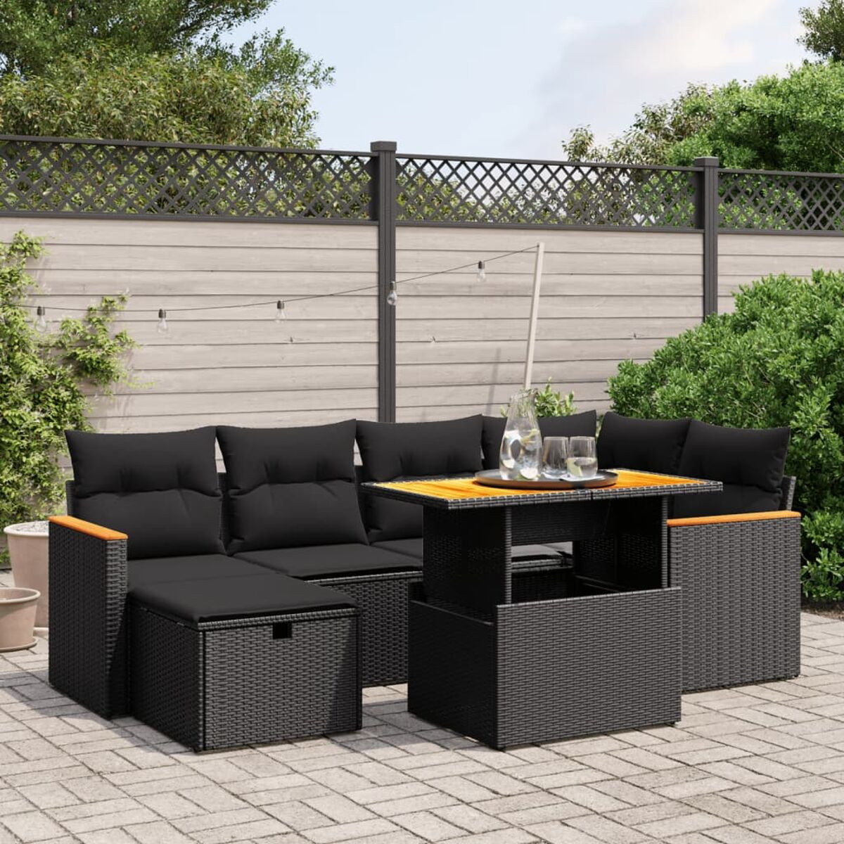 Outdoor-Ecksofa-Set mit Tisch. Schwarze Korbmöbel mit schwarzen Kissen.