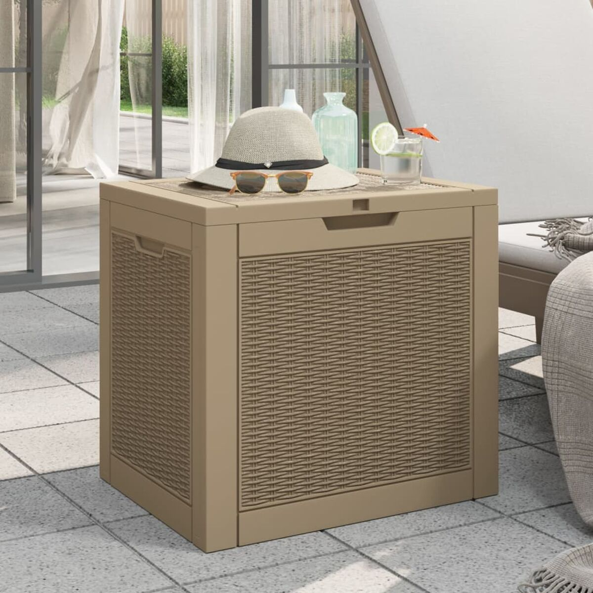 Quadratische Aufbewahrungsbox aus Rattan. Hat einen Deckel und steht auf einer Terrasse.