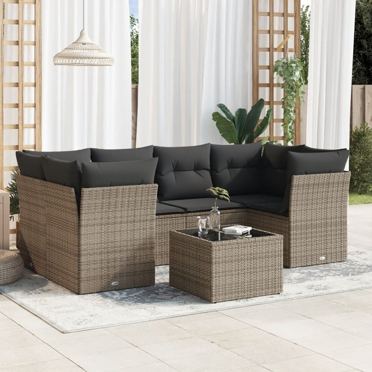 Gartenmöbel-Set aus Korbgeflecht mit Kissen, Couchtisch und dekorativen Elementen.