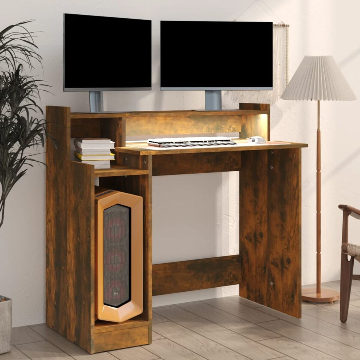 Ein Holzschreibtisch mit zwei Monitoren, einem Computerturm und einer Lampe. Es ist in einem Raum.