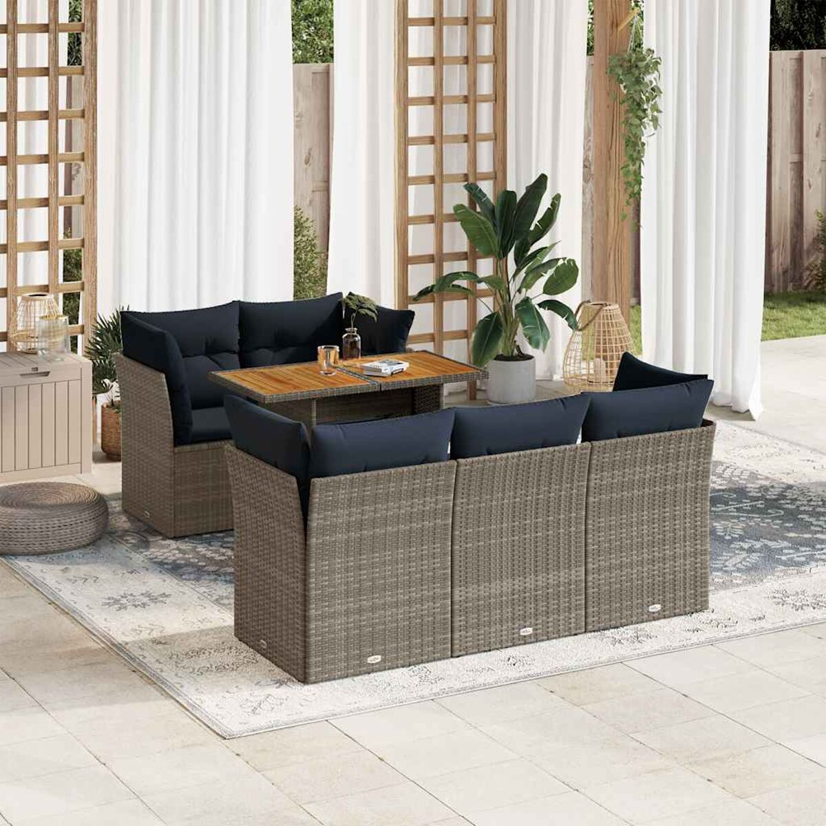 Sitzgruppe im Freien. Ein Tisch, Sofa und Stühle. Dunkelblaue Kissen auf den Sitzen.