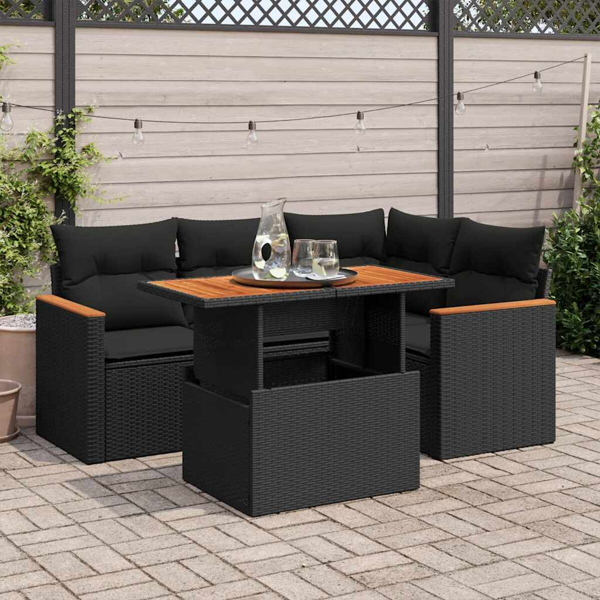 Set da patio in rattan nero con tavolo elevabile, cuscini e piano in legno.