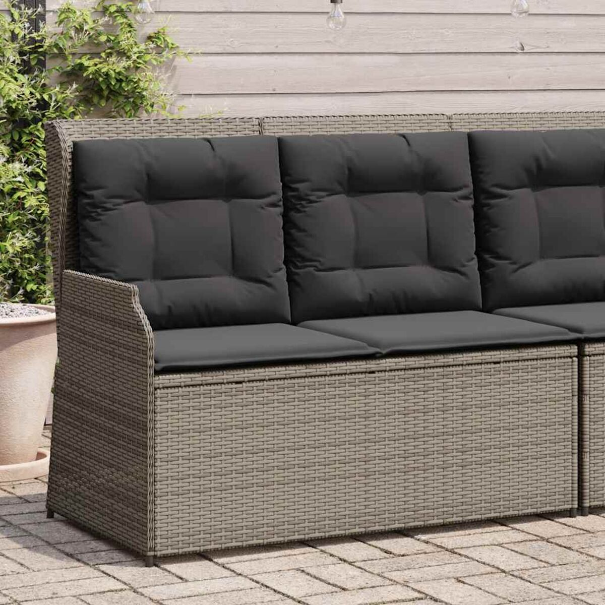 Gewebenes Outdoor-Sofa mit grauen Kissen. Das Sofa hat drei Kissen.