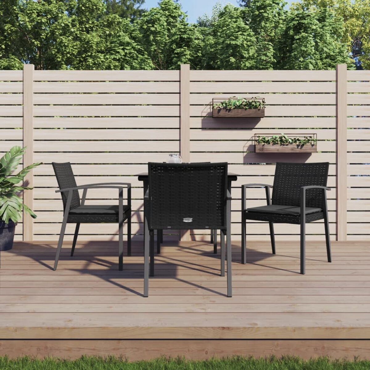 Essgruppe für den Außenbereich mit schwarzen Korbstühlen und Tisch, Holzterrasse und Wandpflanzgefäßen.