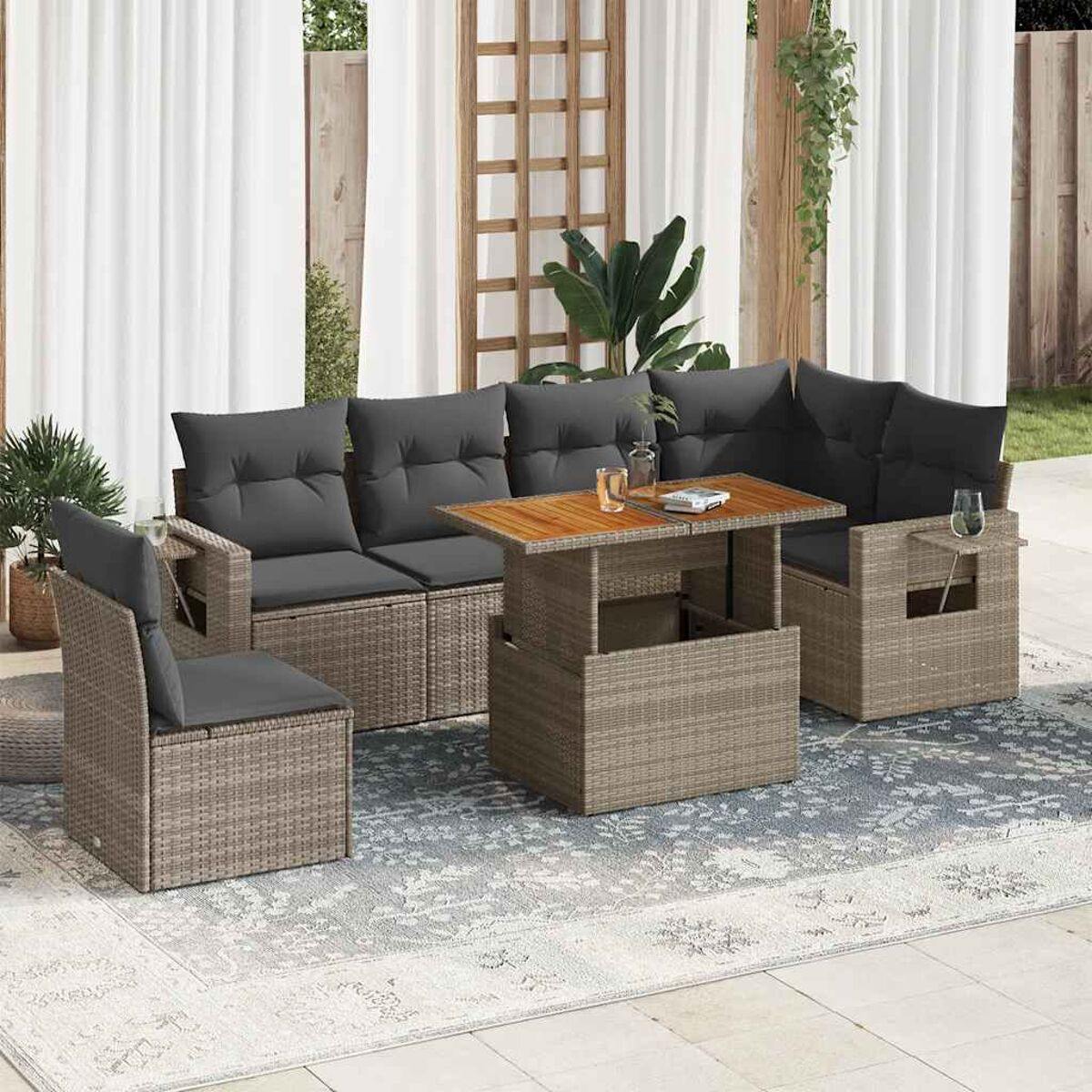 Set di mobili da esterno in rattan, tra cui divano, due sedie e tavolo, su un tappeto.