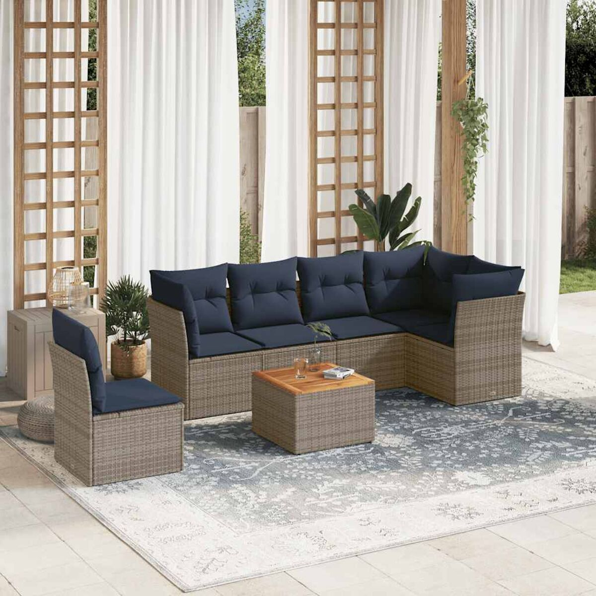 Set da patio esterno con cuscini blu. Divano, sedia, tavolo e tappeto. Tende bianche sullo sfondo.