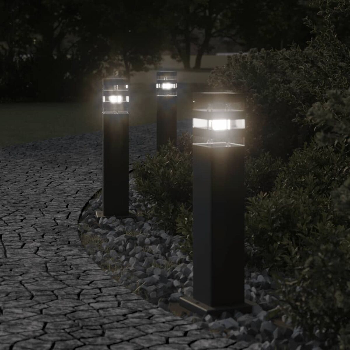 Drei beleuchtete schwarze Pollerleuchten in einem Garten bei Nacht.